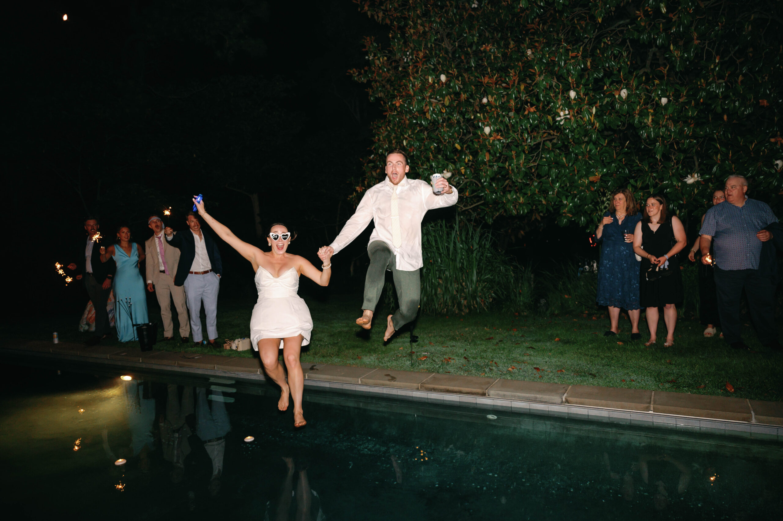 couple jumping into pool wedding exit candid documentary photography