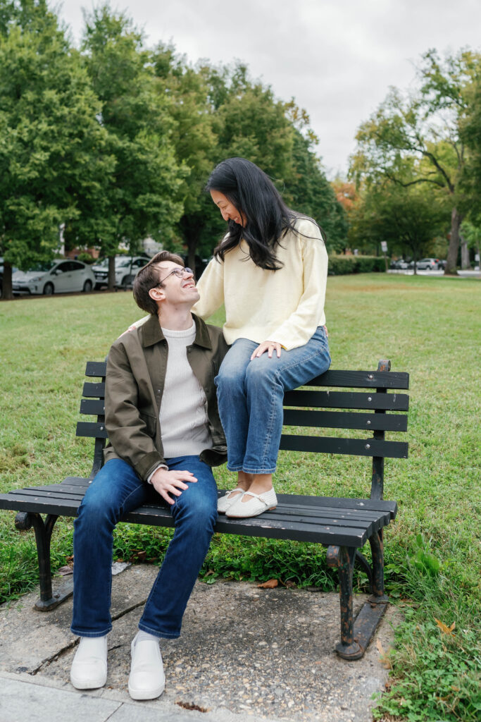 Couple sitting together on park bench during Washington DC engagement session in Capitol Hill