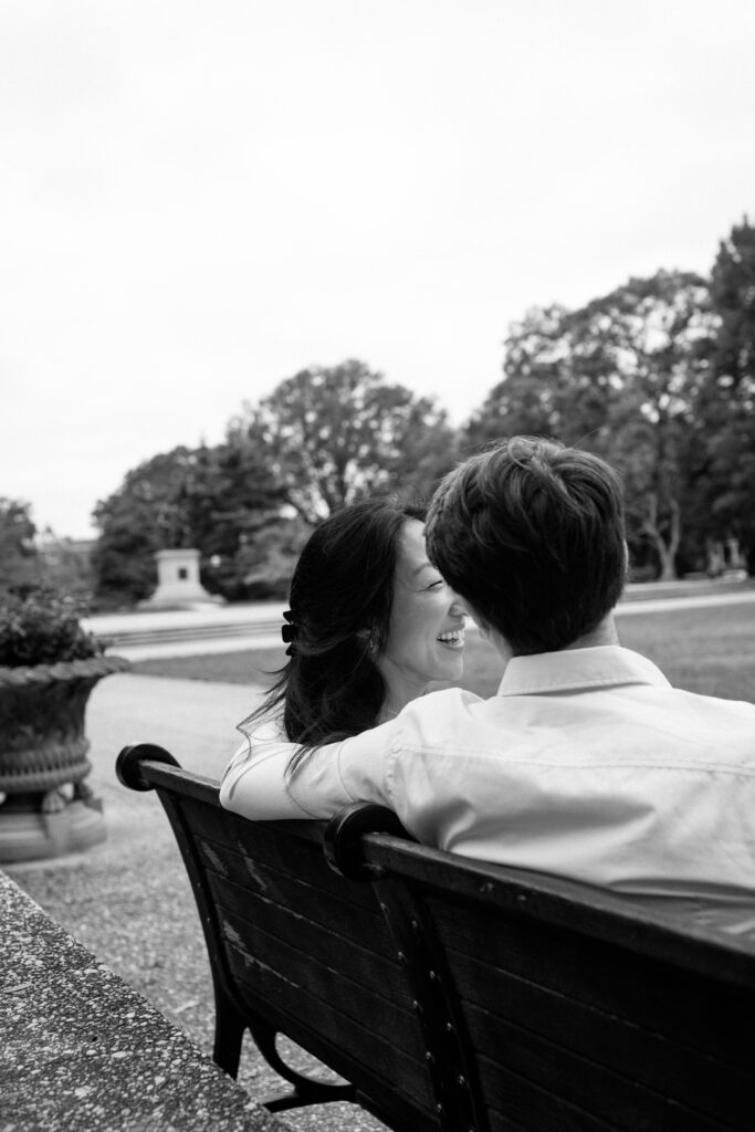 Couple sitting on park bench overlooking Washington DC park during engagement session