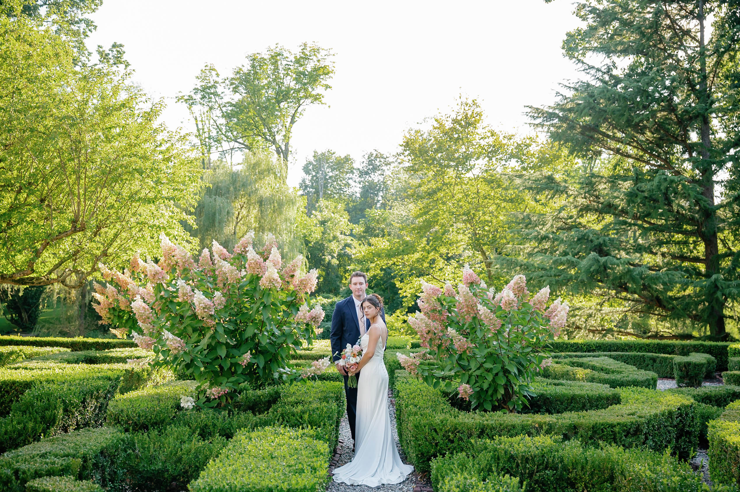 Bride and groom portrait in the boxwood garden at Appleford Estate in Villanova Pennsylvania during a summer wedding.