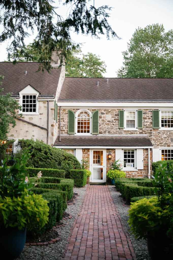 Historic stone exterior of Appleford Estate surrounded by manicured gardens and brick pathways in Villanova, Pennsylvania.